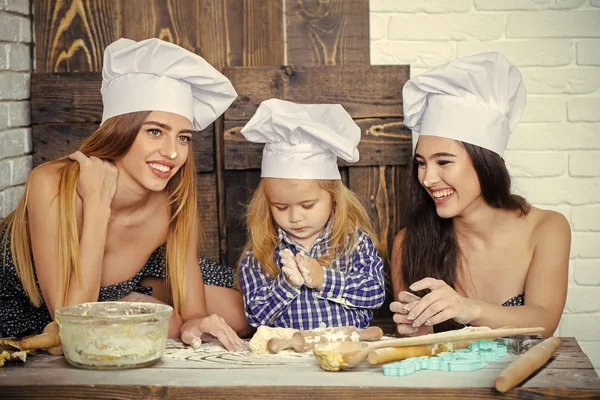 Irmão e irmãs à mesa usando utensílios de cozinha — Fotografia de Stock