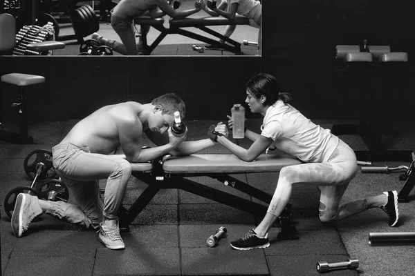 Armwrestling muskulöse Mann und Mädchen in der Turnhalle — Stockfoto