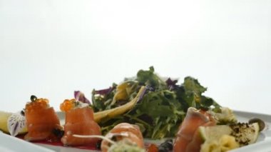 Lezzetli kırmızı balık veya plaka üzerinde bulanık renkli arka plan üzerinde jöle turuncu havyar ve yeşil salata karışımı ile Somon rulo. Modern moleküler Gastronomi.