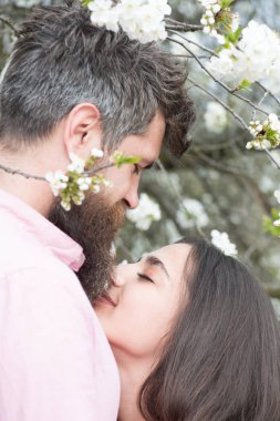 Çift Romantik tarihte pastoral Bahçe, bahar kavram aşık. Sakallı adam çiçek açması ağacının yan görünümü şık adam yanındaki şirin kız ve çiçek arka plan güneşli günde güzel kadının öpüşme.