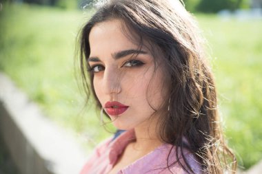 Kadın sakin yüz makyaj ile arka plan, doğa defocused. Uzun saçlı kız güneşli günde açılarak gömlek giyer. Bayan çekici görünüyor, yakın çekim. Cazibe kavramı.