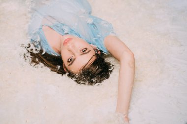 Sevimli kız tüyler, tatlı rüyalar kavramı ile yumuşak yatakta yatıyordu. Yatak odasında poz mavi elbiseli dolgun dudaklar esmer kadın.