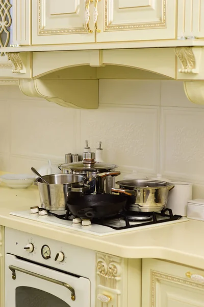 Stove with pots and pans on countertop. Stove with cooking utensils on white wall tile. Kitchen appliance and furniture. Kitchen design in vintage style. Cooking at home concept.