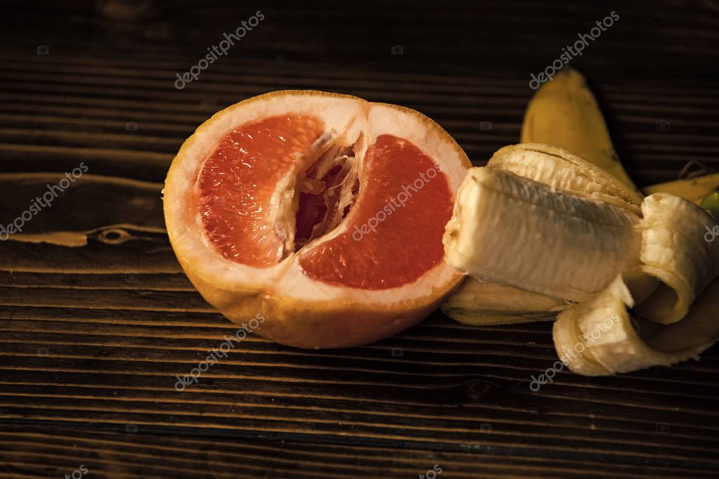 Penis and vagina banana with yellow peel in red grapefruit Stok  