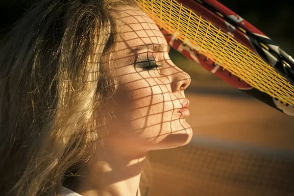 Girl athlete with net shadow on face on sunny day