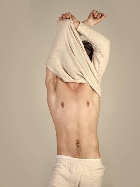 Erkek Bakım iyileştiriyor. Uykulu adam soyunmak gri arka plan üzerinde.