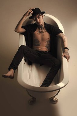 Adam siyah şapka ve kıyafet banyo sekmede yalan