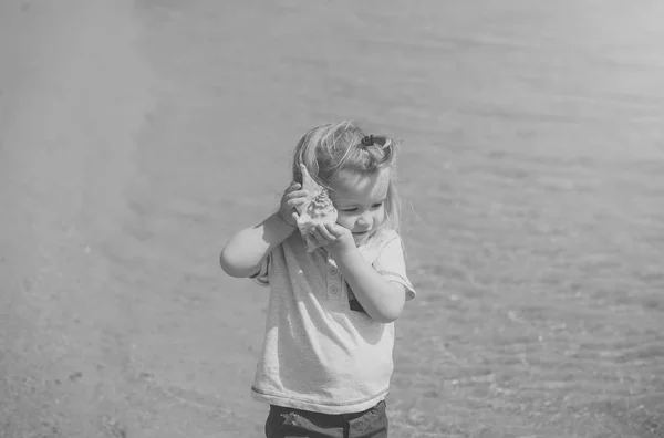 Niño escuchar concha marina en el día soleado — Foto de Stock