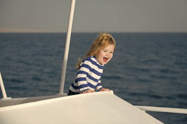 Teknede çizgili mavi ve beyaz gömlekli çocuk.