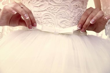 Gelin kızın ellerini beyaz yay gelinlik üzerinde tutun.