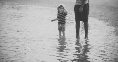 Çocuk yetişkin gözetiminde yürüyüş suda deniz kumsalda