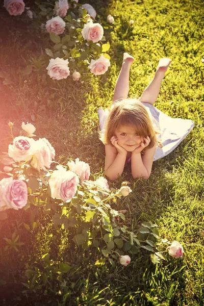 Дитячий енйой щасливий день. Дівчина лежить на зеленій траві в літньому саду — стокове фото