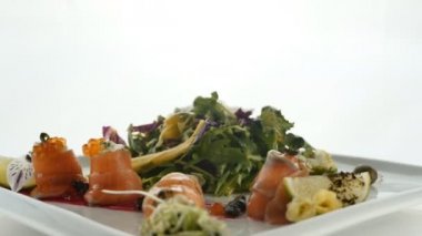 Lezzetli kırmızı balık veya plaka üzerinde bulanık renkli arka plan üzerinde jöle turuncu havyar ve yeşil salata karışımı ile Somon rulo. Modern moleküler Gastronomi.