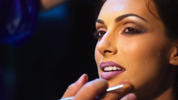 Make-up artist om ljusa läppstift på modeller läppar. Makeupartist gör makeup för flicka inomhus. — Stockvideo
