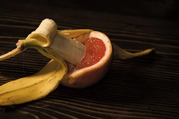 Μπανάνα με κίτρινο φλοιό στο κόκκινο γκρέιπφρουτ — Φωτογραφία Αρχείου
