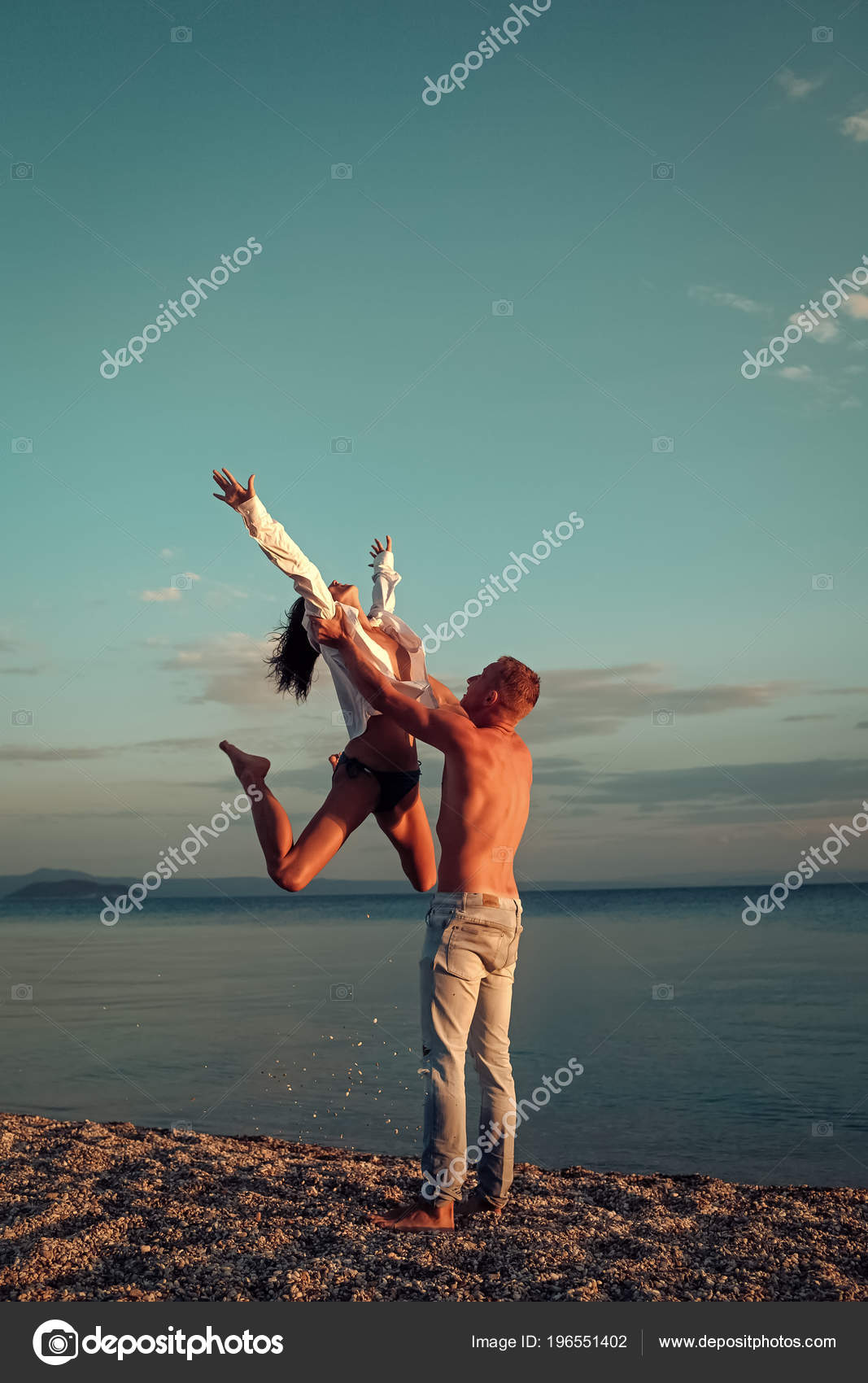 Cheerful couple having some good time naked on the beach