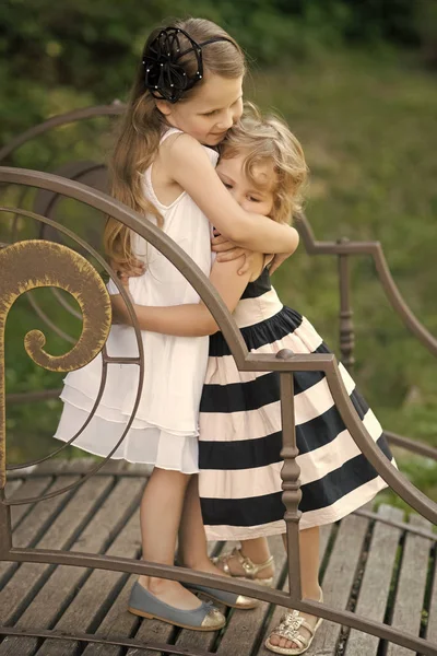 Chico feliz divirtiéndose. Niñas o hermanas se abrazan en el puente en el día de verano —  Fotos de Stock