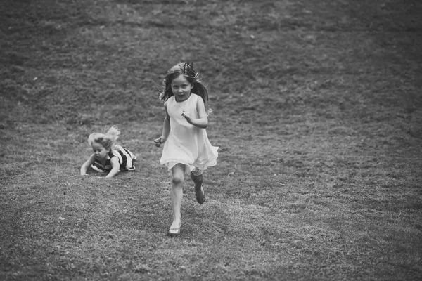 Kind jeugd kinderen geluk Concept. Kinderen lopen en vallen op groen gras op zomerdag — Stockfoto