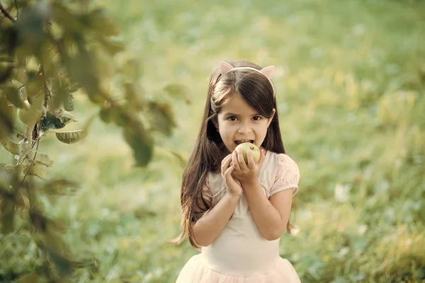 Miúdo feliz a divertir-se. Menina come maçã no fundo natural, vitamina — Fotografia de Stock