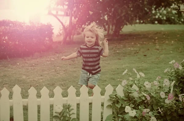 Kinderen spelen met speelgoed. kind of kleine jongen buiten in de buurt van witte houten hek — Stockfoto