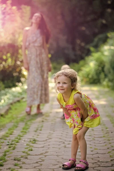 Chico feliz divirtiéndose. Chica hija feliz con pelo rubio rizado caminar con la madre — Foto de Stock