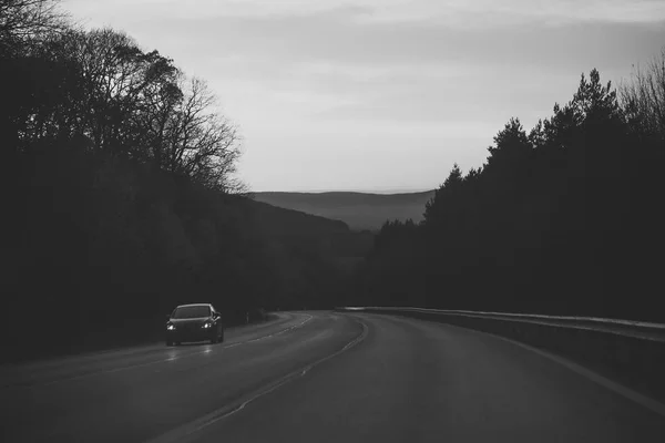 路与汽车驱动在山, 森林在日落天空 — 图库照片