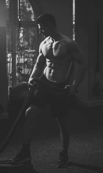 Αθλητικός τύπος, αθλητής με μυς ασκεί με σχοινιά. Έννοια άθλημα και γυμναστήριο. Άνθρωπος με γυμνό τον κορμό σε γυμναστήριο, Απολαύστε τον αθλητικό τρόπο ζωής. Ο άνθρωπος με τον κορμό, μυϊκή macho κάνει λειτουργική εκπαίδευση. — Φωτογραφία Αρχείου