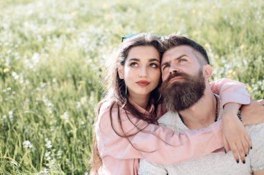 Sakal ve kadın oturur bahar günü çimenlerin üzerinde olan adam. Bahar eğlence kavramı. Mutlu rüya gibi yüzleri çayır, Doğa arka plan üzerinde oturan bir çift gördüm. Aşık çift harcamak zaman açık havada ve hugs.