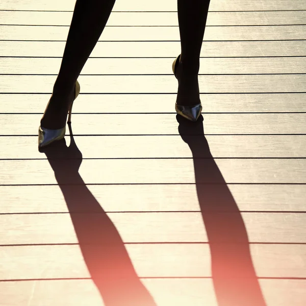 Γυναικεία πόδια σε χρυσά παπούτσια με ψηλά τακούνια και σκιά — Φωτογραφία Αρχείου