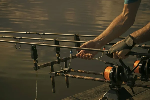 Стержни, катушки, линии и мужские руки на водном фоне, рыбалка — стоковое фото
