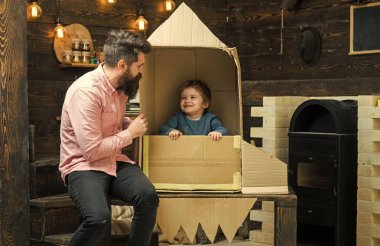 Baba, Baba, küçük kozmonot ile Çocuk oyun karton kutudan yapılan roket oturup. Çocuk mutlu oturmak karton el roket yapımı. Çocuk Çocuk oyun kozmonot, astronot. Ebeveynlik kavramı