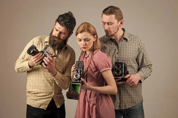 Handsome man face. Men in checkered clothes, retro style. Vintage photography concept. Company of busy photographers with old cameras, filming, working. Men, woman on interested faces looks at camera.
