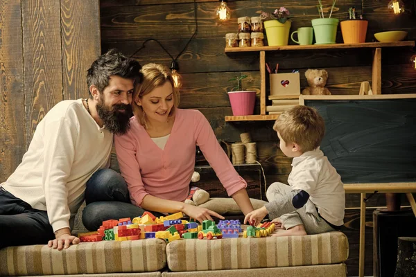 Kids playing with toys. Father, mother and cute son play with constructor bricks. Caring parents concept. Family on busy face spend time together in playroom. Kid with parents play with plastic blocks
