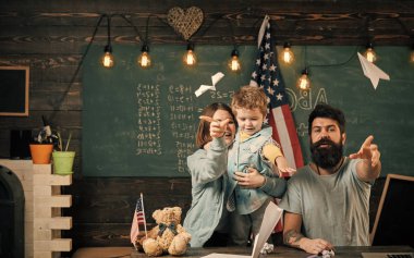 Çocuk oyun. Resepsiyon ile kağıt uçak yapma evlat, Amerikan ailesi. Evde eğitim kavramı. Anne oğlu Amerikan gelenekleri oynarken öğretim. Sınıf ABD bayrağı, kara tahta ile ebeveynler çocuk