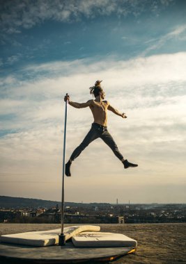 Seksi maço adam gökyüzü arka plan üzerinde uçmak. Pole dans spor. Güçlü adam dansçı egzersiz kutup. Atletik adam pilon üzerinde akrobatik öğeleri olun. Pilon üzerinde dans genç adam. Doğru sağlıklı yaşam tarzı