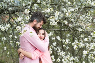 Bahar tarihi kavramı. Çift çiçek açan ağaçlar sarılmak. Çiçek Bahçe erkek ve kadın hugs bahar gününde. Aşık çift bahar bahçe, dalları zemin üzerine çiçekli zaman harcamak.