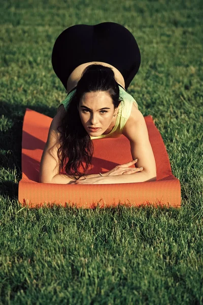 Fitness kvinna med hästsvans göra planka position på grönt gräs — Stockfoto