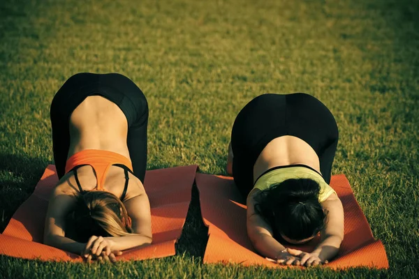 Athletes do yoga exercises on green grass — Stock Photo, Image