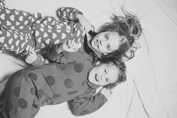 Діти грають - щаслива гра. Дівчата-сестри в піжамах щаслива посмішка в ліжку, вид зверху — стокове фото
