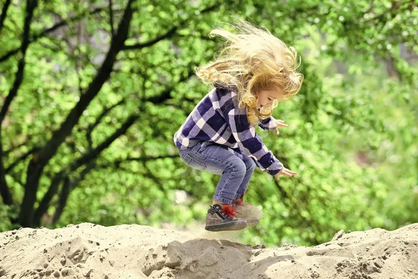 Un enfant heureux qui s'amuse. Enfant rebondir sur le sable au printemps ou en été parc — Photo