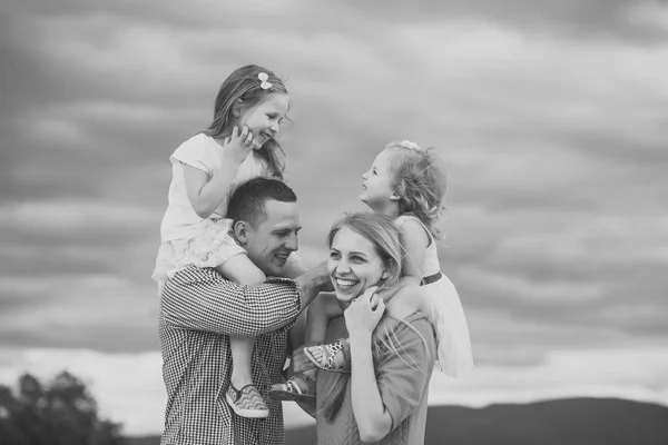 Концепция счастья детей детского детства. Девочки сидят на материнских плечах отца на облачном небе — стоковое фото