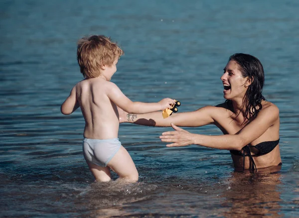 海の母親でかわいい子男の子遊び海 お母さんと子供は笑顔が 晴れた日に一緒に海で時間を過ごします 母性の概念 海と子供に見える母のスイミング — ストック写真