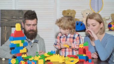 Genç aile oyun odası. Aile kavramı seviyorum. Anne, baba ve çocuk oyuncakları ile dışarı plastik blokları inşa. Anne ve oğlu gülümseyen, tuğla yapılar yapmak.