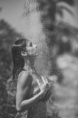 Kız desteklenmektedir. Sorunları kızlar yüz. Su üzerinde çekici kadın düşüyor düşüyor. Genç güzel esmer kız alma duş plajda yüzme sonra. Bikinili seksi Bayan duş sıcak güneşli günde sahiptir.