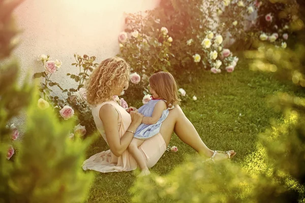 Mulher com menina criança em flores de rosa florescentes — Fotografia de Stock
