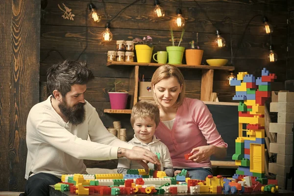 Otec, matka a roztomilý syn hrát s konstruktor cihly. Děti hrají s hračkami. Rodina na obsazeno tvář trávit čas spolu v herně. Vzdělávací hra koncept. Děti s rodiči hrát s plastovým — Stock fotografie