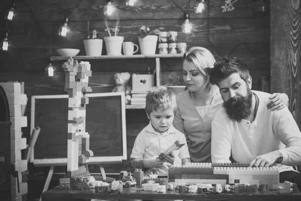 Family leisure concept. Kids playing with toys. Parents hugs, watching son playing, enjoy parenthood. Kid with parents play with plastic blocks, build construction. Father, mother and cute son play — Stock Photo, Image