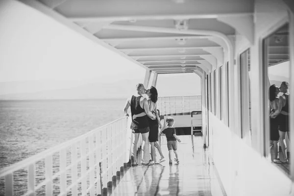 Chico feliz divirtiéndose. Familia viajando en crucero en un día soleado. Concepto de familia y amor. Padre, madre e hijo de pie en la cubierta de crucero con el mar en el fondo. Padres felices besándose cerca — Foto de Stock