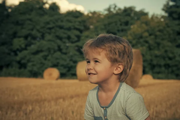 Chico feliz divirtiéndose. Sonrisa infantil en el campo con fardos de heno, agricultura —  Fotos de Stock