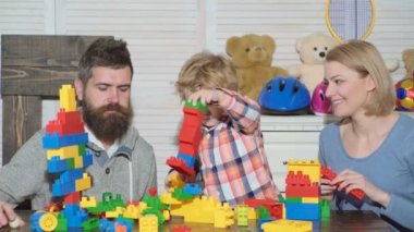 Genç aile oyun odası. Aile kavramı seviyorum. Anne, baba ve çocuk oyuncakları ile dışarı plastik blokları inşa. Anne ve oğlu gülümseyen, tuğla yapılar yapmak.